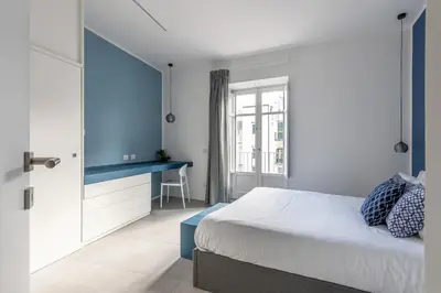 a kitchen with white cabinets and a table and chairs at Casa Azul alla Cala by Wonderful Italy in Palermo