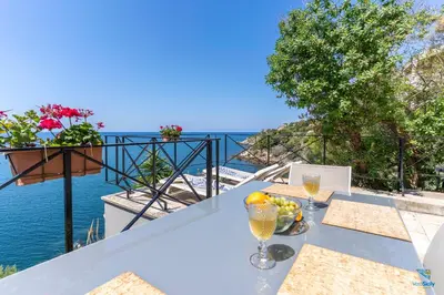 a table with a glass of wine and a bowl of fruit at Vero Sicily - Villa Acqua Chiara in Bagheria