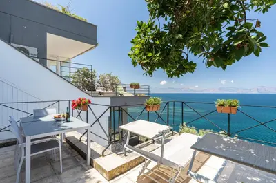 a balcony with a table and chairs and the ocean at Vero Sicily - Villa Acqua Chiara in Bagheria