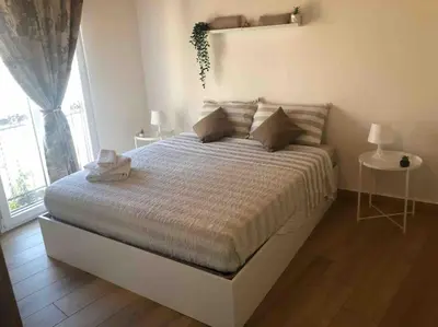 a bedroom with a large bed with a large window at Appartamento NA ME CASA in Palermo