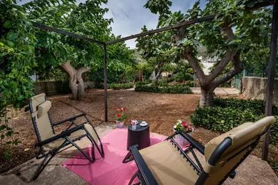 a patio with two chairs and a table with a pink blanket at La Casetta in San Vito lo Capo