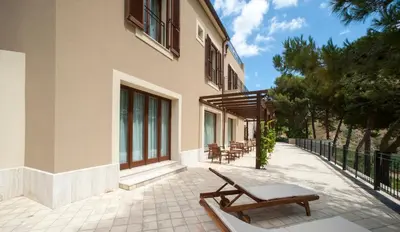 a patio with lounge chairs and a building at Feudo Del Biviere in Santa Ninfa