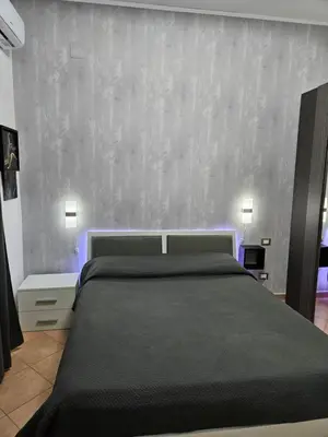 a bedroom with a large bed and a concrete wall at Simone Cupolas View in Palermo