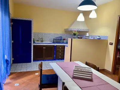 a kitchen with a dining table and a blue door at Sicilian Apartment in Termini Imerese