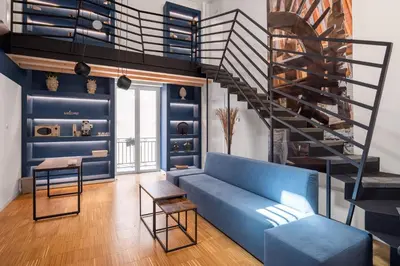 a living room with a blue couch and a spiral staircase at Le Stanze di Triyah in Palermo