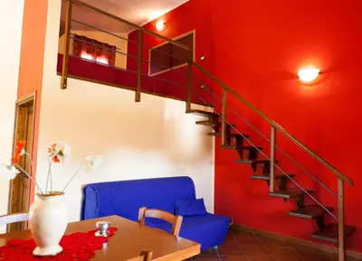 a living room with a blue chair and a staircase at Case Vacanza Longo in Balestrate
