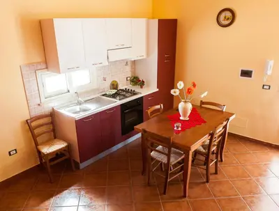 a kitchen with a wooden table and a table and chairs at Case Vacanza Longo in Balestrate