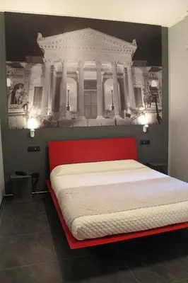 a bedroom with a red bed with a building on the wall at Alma Hotel in Palermo