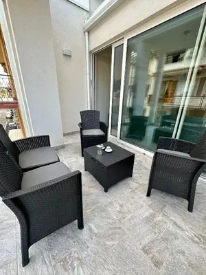 a patio with chairs and a coffee table and a building at The White Lodge in Porticello