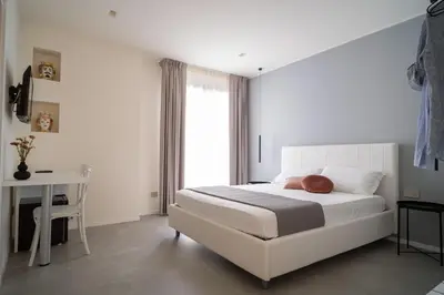a bedroom with a bed and a desk and a window at Acquamarina Rooms in Castellammare del Golfo