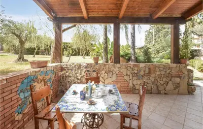 a table and chairs on a patio with a stone wall at 3 Bedroom Lovely Home In Borgetto in Borgetto