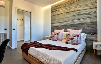 a bedroom with a large bed with a wooden wall at Beautiful Apartment In Trappeto in Trappeto