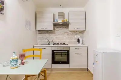 a kitchen with white cabinets and a table and a white refrigerator at Talia Capo Massimo in Palermo
