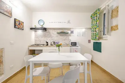 a white kitchen with a white table and chairs at Talia Capo Massimo in Palermo