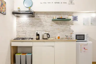 a kitchen with white cabinets and a brick wall at Talia Capo Massimo in Palermo