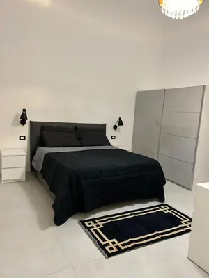 a white bedroom with a black bed and a chandelier at margot palermo in Palermo
