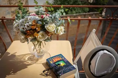 a table with a vase of flowers and a book at Sunshine Apartments in Trappeto