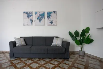 a living room with a couch and a potted plant at CAMA Casa Vacanze - Qui vivi la vera storia normanna in Palermo