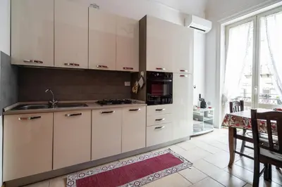a kitchen with white cabinets and a sink and a table at Plumeria Vacanze in centro a Palermo- Isidoro Carini zona Politeama in Palermo