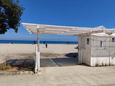 a white building on a beach with people on the beach at Mondello La Piazzetta Apartment in Palermo