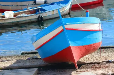 a red white and blue boat sitting on the shore at Mondello La Piazzetta Apartment in Palermo