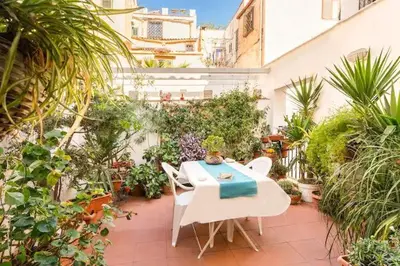 a patio with a table and chairs and plants at At Kalsa Quiet Flowered Terrace! Free Parking! Ideal for remote working! in Palermo