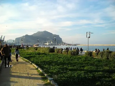 a group of people walking down a sidewalk near the water at At Kalsa Quiet Flowered Terrace! Free Parking! Ideal for remote working! in Palermo
