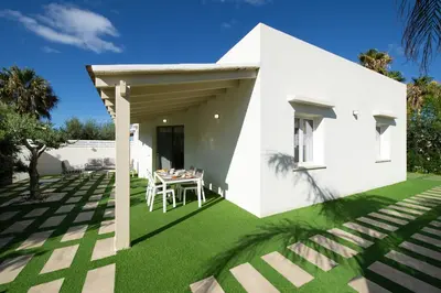 a white house with a green lawn at Villa Charme in San Vito lo Capo