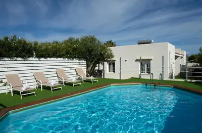 a swimming pool with chairs and a house at Villa Charme in San Vito lo Capo