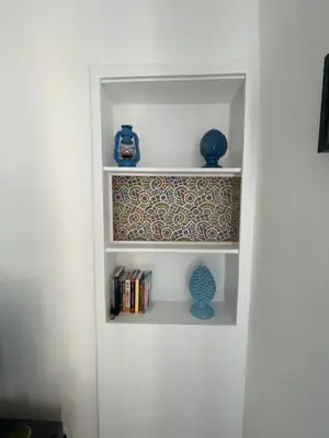 a white book shelf with some blue vases and books at Mondello - La casa del vecchio pescatore in Palermo