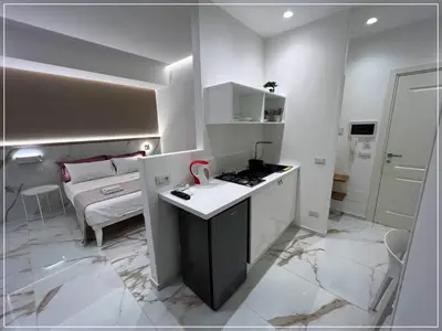 a kitchen with a counter and a room with a bed at ARIOSTO HOME in Palermo