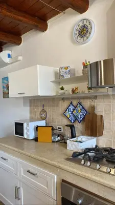 a kitchen with a counter top with a stove and a clock at Casetta Matotta, casa vacanze a Mondello - Palermo in Mondello