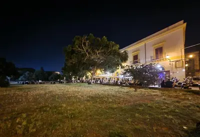 a group of people sitting outside of a building at night at Tuttoporto-Apartments LEVANTE in Palermo