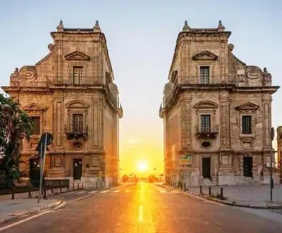 two buildings on a street with the sunset in the background at Tuttoporto-Apartments LEVANTE in Palermo