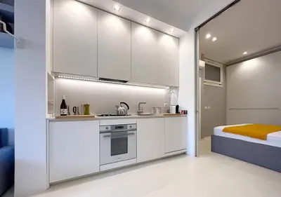 a kitchen with white cabinets and a bed in a room at Solemar Sicilia - White Loft in Palermo
