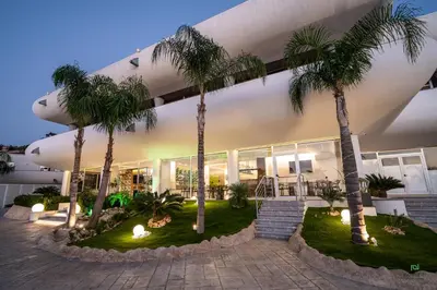 a building with palm trees in front of it at New River Hotel in Borgetto