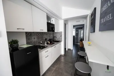 a kitchen with white cabinets and a black refrigerator at New River Hotel in Borgetto