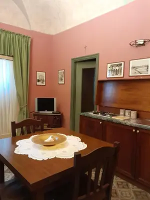 a dining room with a table and a kitchen at Casa Castelli Holiday Apartment in Bagheria