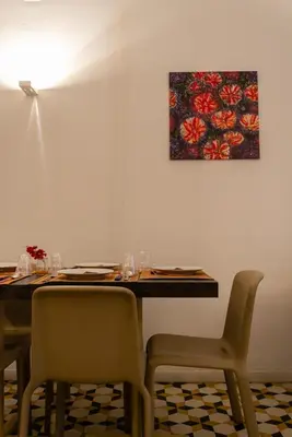 a table with chairs and a painting on the wall at C'era Una Volta in Palermo