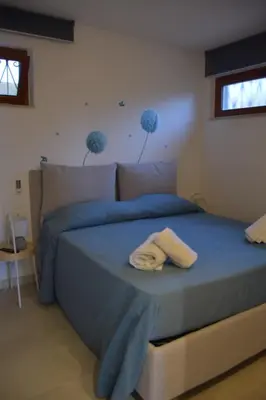 a bedroom with a bed with blue sheets and two windows at Caladdaura in Palermo