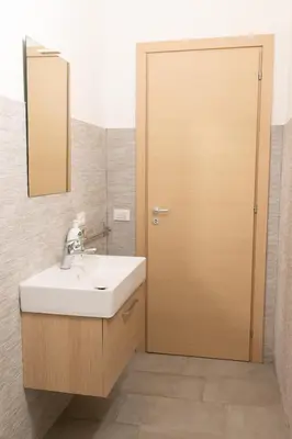 a bathroom with a sink and a wooden door at Villa Mare E Monti in Castellammare del Golfo