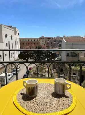 two coffee cups sitting on a yellow table on a balcony at Monkey house Appartamento in centro storico in Palermo