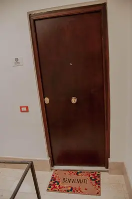 a brown door with a welcome mat in front of it at Ideisini's apartment in Palermo