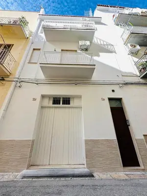 a white building with two doors on the side of it at Amalcamo Apartments in Alcamo