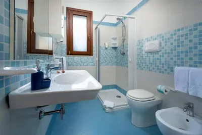 a blue tiled bathroom with a sink and a toilet at B&B Armonie in San Vito lo Capo