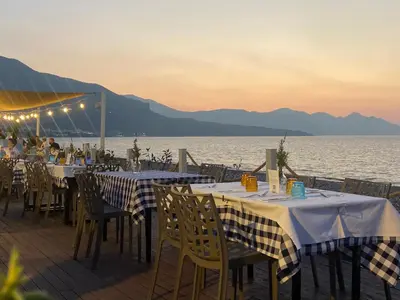 a group of tables and chairs on a deck with the water at Addauro in Alcamo