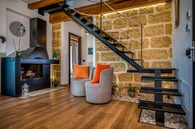 a living room with a stone wall and stairs at Villa Pharus Scopello in Scopello