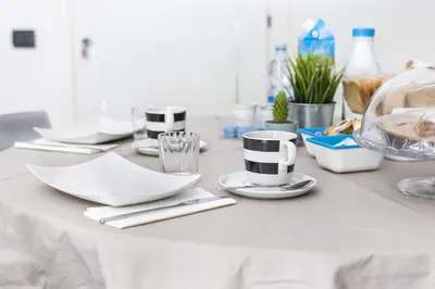 a table with white dishes and cups on it at B&B Porta delle Madonie in Campofelice di Roccella