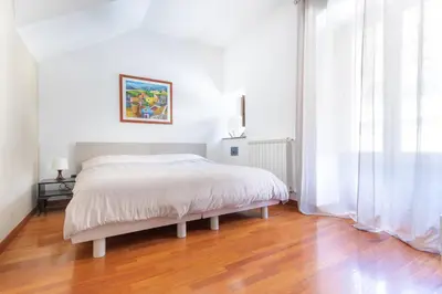 a white bedroom with a bed and a wooden floor at B&B Porta delle Madonie in Campofelice di Roccella