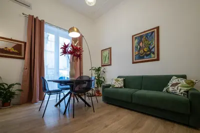 a living room with a green couch and a table at La Premiere Suite - Teatro Massimo Palermo in Palermo